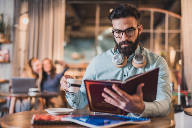 istock Male student drinking coffee and reading a book. 1309722204