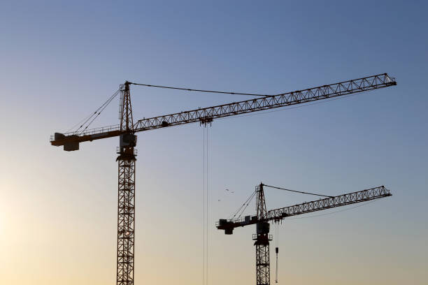 istock Two tower cranes against blue sky at sunrise 1309722224