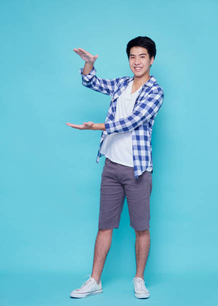 istock Asian handsome man presenting on blue background 1309722282