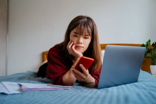 giovane donna stressata che usa lo smartphone sul letto - smart phone china mobile phone asia foto e immagini stock