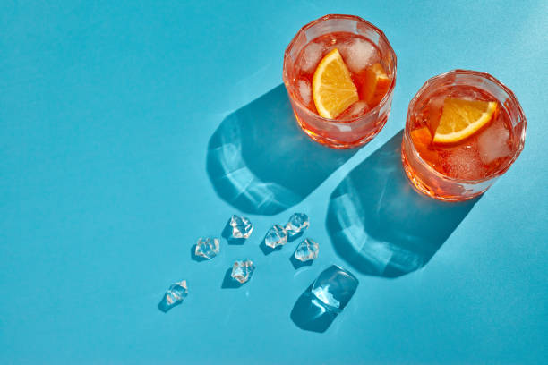 cocktail. due bicchieri con bevande fresche, arance a fette e ghiaccio su sfondo blu con ombra. visualizzazione dall'alto con spazio di copia - bevanda fredda foto e immagini stock