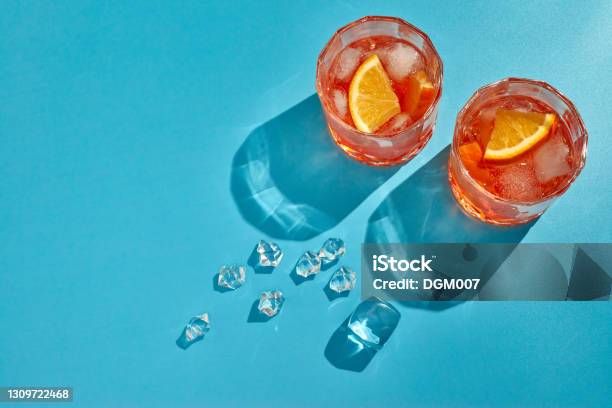 Cocktail Two Glasses With Cool Beverages Sliced Oranges And Ice On Blue Background With Shadow Top View With Copy Space Stock Photo - Download Image Now