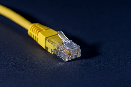 Technology and computer network concepts. Yellow color network jack (plugin) on dark background with copy space.