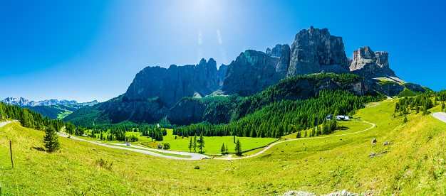 Italian mountains near the Langkofel Group, and green meadows on a sunny cloudless day. High resolution panorama.