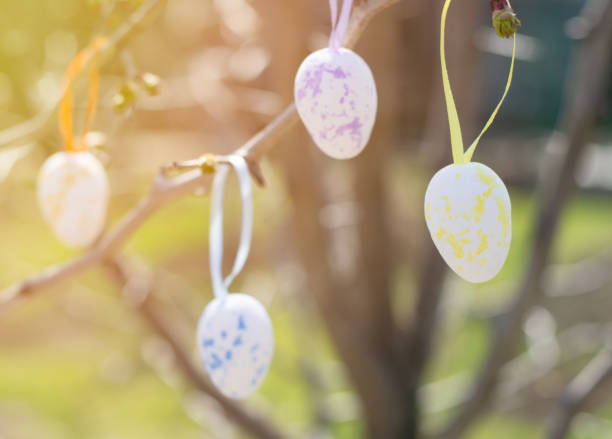 istock Easter colorful eggs hang from the branches of a tree in the rays of sunlight. Easter composition 1309725698