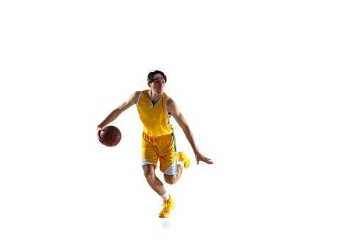 Young Caucasian basketball player, basketballer in yellow sports uniform training isolated on white background. Action, dynamic. Concept of active life, team game, energy, sport. Copy space for ad.