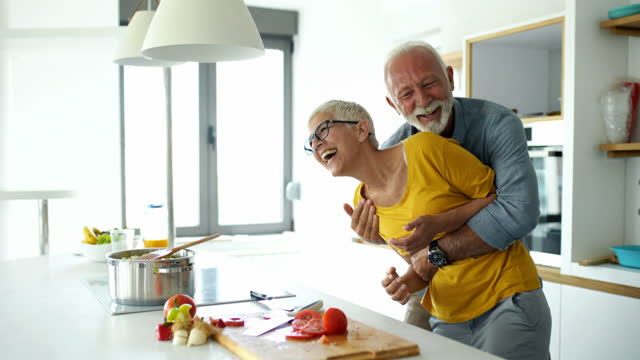 Mature couple having fun while cooking lunch.