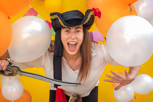 Woman in pirate costume with bright balls on orange background