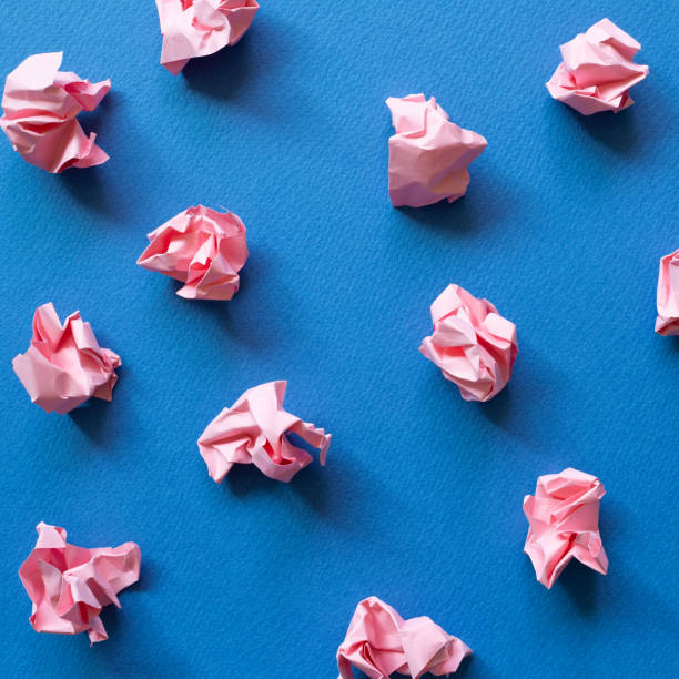 istock Pink crumpled paper balls on blue background. Creative idea concept 1309731477