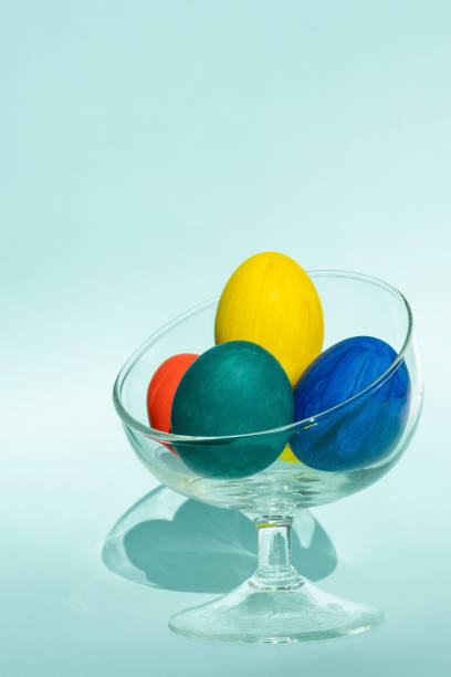 istock Hand-painted colorful Easter eggs in a transparent glass vase against a light blue background, vertical frame 1309731601