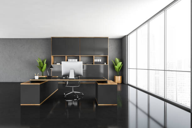 istock CEO office interior with a wooden table, a computer standing on it. Black floor. Panoramic city view window 1309734552