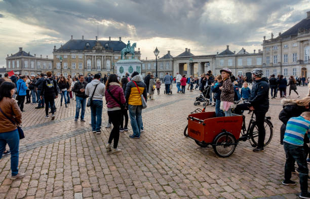 Copenhagen, Denmark - Oct 19, 2018: Tourists crowd the open court at Amalienborg Square (Queens winter residence). Classic European architecture around with cobblestone flooring.