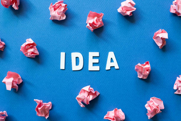 istock Pink crumpled paper balls on blue background. Creative idea concept 1309734852