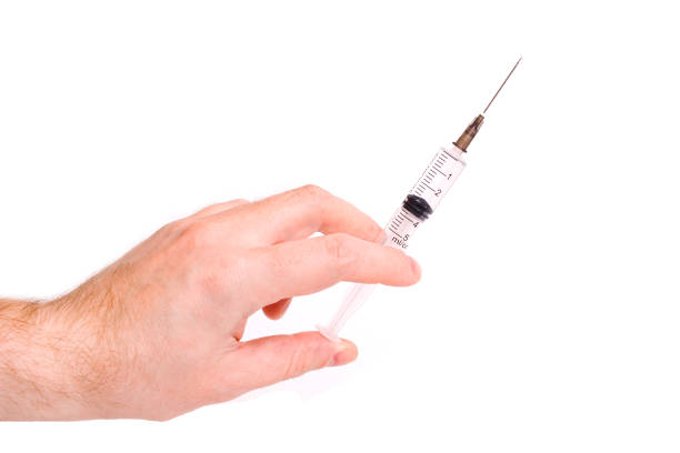 istock Syringe in hand on white background closeup 1309734973