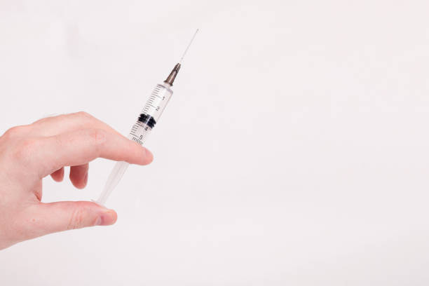 istock Syringe in hand on white background closeup 1309734998