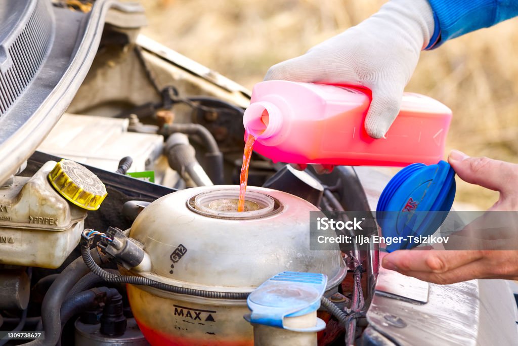 Pouring coolant Service of cars. Pouring antifreeze. Mechanic fills the coolant G12 to tank in the engine Pouring coolant, Service of cars. Pouring antifreeze. Mechanic fills the coolant G12 to tank in the engine. Automobile maintenance, coolant exchange in old car Coolant Stock Photo
