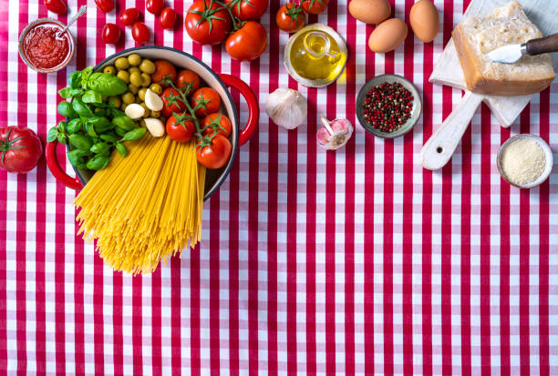 Spaghetti basil tomato garlic and olives in pot on gingham tablecloth