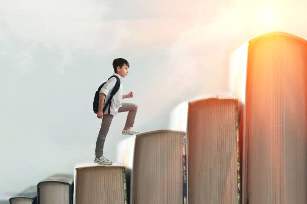 Child climbing stairs made of on sky background. Education or hard study concept. Soft focus Child climbing stairs made of on sky background. Education or hard study concept. Soft focus only boys stock pictures, royalty-free photos & images