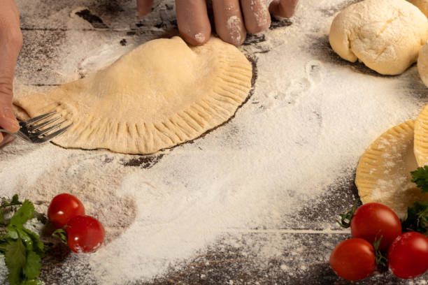 istock The cook prepares pasties. Step-by-step instruction. Forms the dough. Wooden background. 1309741342