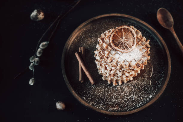istock fresh waffles on a wooden plate, sprinkled with powdered sugar. waffles, quail eggs and nuts on a black background 1309743626
