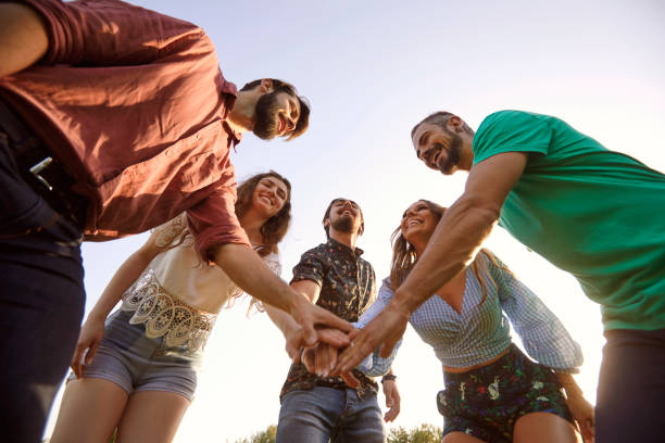 istock Low angle view of young smiling friends putting hands together in circle, outdoors. Unity or support concept 1309746059