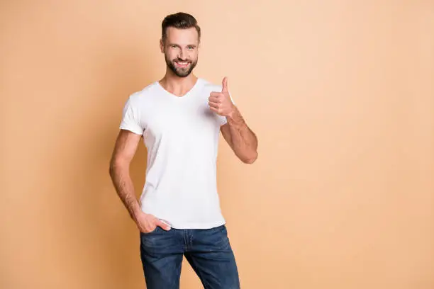Photo of young stubble man happy positive smile show thumb-up advert like cool perfect isolated over beige color background.