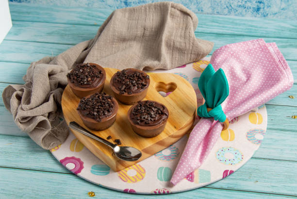 istock Four small chocolate-flavored brigadier cakes on an Easter table with pink napkin, napkin ring similar to rabbit ears, a themed sousplat and wooden stand. Blue background. 1309748818