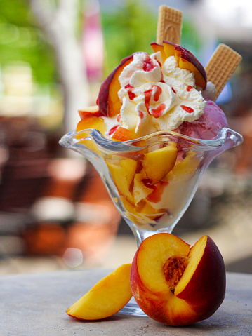 View of a Decorated peach sundae with ice cream, whipped cream, waffles and fruits. For ice cream parlors, restaurants and cafes. copy space