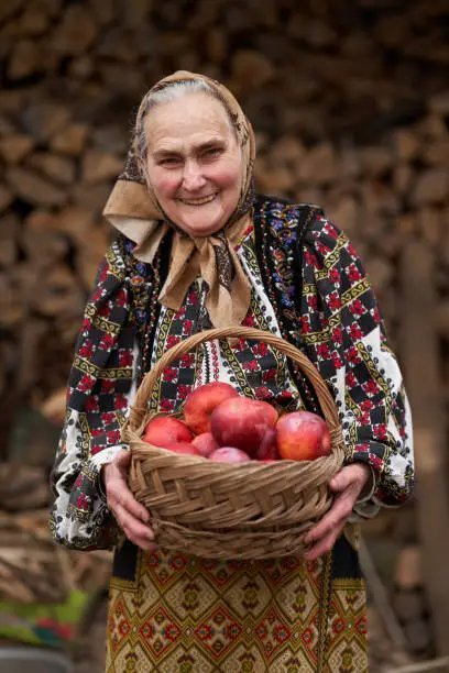 Photo of Old woman with a basket of apples outdoor