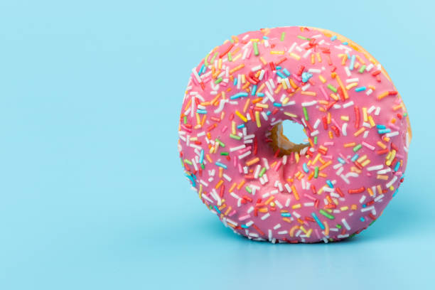istock Fresh made Donuts isolated on blue background. Doughnuts are traditional sweet pastries. Copy space for text. 1309754823