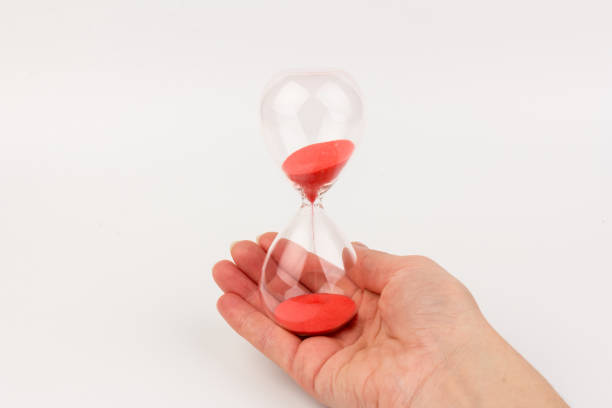 istock Hand holding a hourglass isolated on white background 1309754893