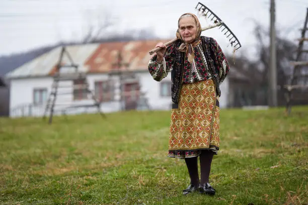 Photo of Old farmer woman cleaning with a rake