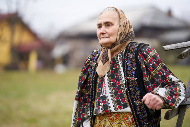 Old Romanian woman in traditional popular costume outdoor in her garden