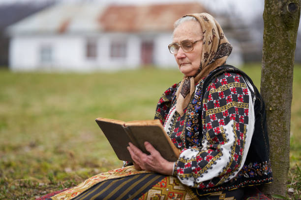istock Old woman reading a book outdoor 1309755081