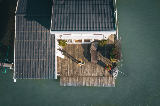 Drone view of lake house rooftop with woman on deck