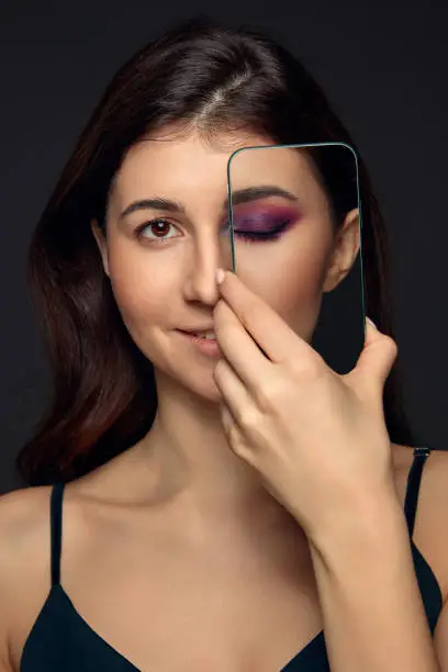 Photo of Lie and another life in social media. Girl with make up in photo frame and no make up in real life. Playing pretend.