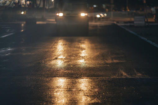 Steamroller compacting asphalt on city street at night