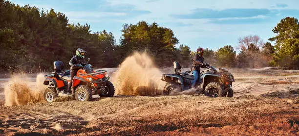 Teen riding ATV in sand dunes making a turn in the sand