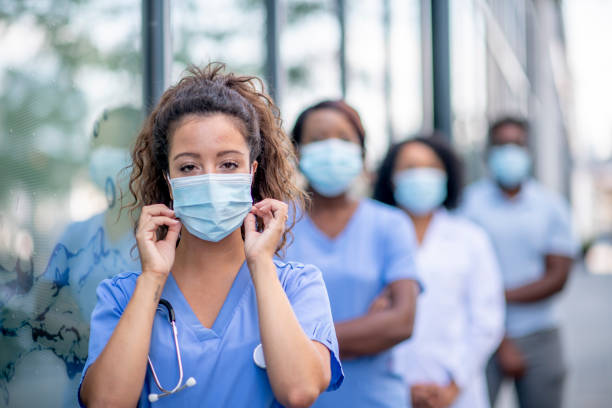 istock Female doctor adjusting her face mask while standing outdoors 1309759283