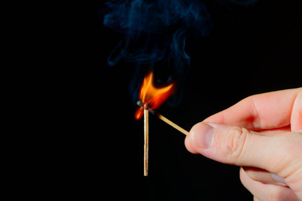 istock burning match in his hand ignites a second match on a black background 1309760497