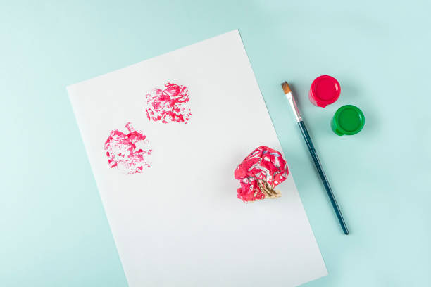 istock DIY and kids creativity. Step by step instruction: how to draw flowers painting techniques with crumpled newspaper. Step2 Dip newspaper in paint and make prints on white paper. Children Craft, drawin 1309761813