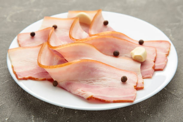 istock Fresh raw slices bacon on plate on grey background. Vertical foto 1309764512