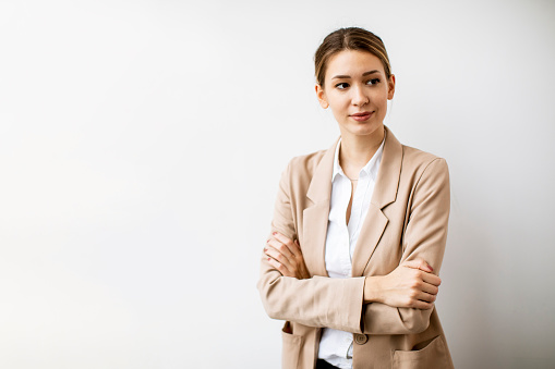 Pretty young woman standing by the white wall in modern office