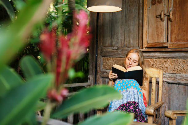 istock Young woman read paper book on outside veranda 1309768331