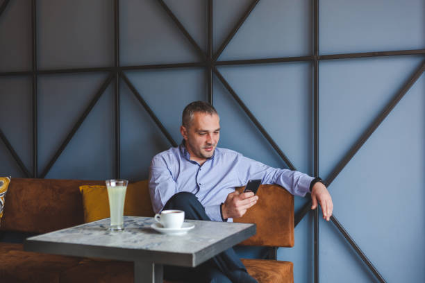 istock Smiling businessman reading a text message on smart phone in a cafe. 1309769429