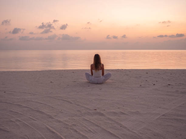 Woman exercising yoga at sunrise on the beach Beautiful woman exercising yoga at sunrise enjoying sea view the beach. tranquil scene stock pictures, royalty-free photos & images