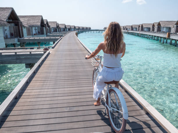 istock Young woman riding bicycle in tropical paradise 1309771364