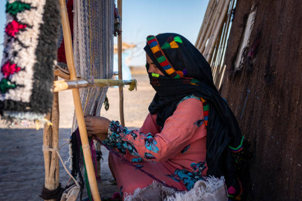 a berber woman weaves using a traditional loom in a village - berbere imagens e fotografias de stock