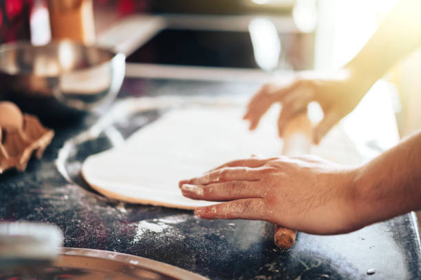 istock Man makes pizza at home in the kitchen. Rolls out the dough with rolling pin 1309775959