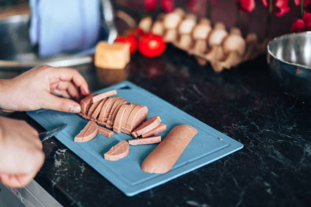 istock Man makes pizza at home in the kitchen. Cuts the pizza sausage into strips 1309776008